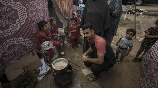 People cook food inside a tent complex in a tent camp provided by the United Nations Development Programme (UNDP) for displaced Palestinians who lost their homes in the Israeli bombardment, in Khan Yunis, 29 October 2023