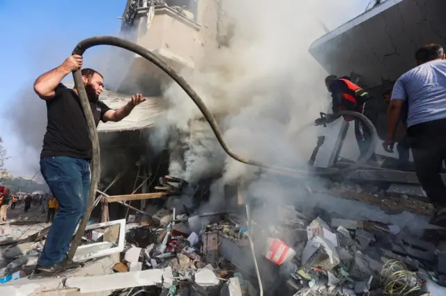 A firefighter, with the help of a Palestinian man, works at the site of Israeli strikes on a residential building, amid the ongoing conflict between Israel and Palestinian Islamist group Hamas, in Khan Younis in the southern Gaza Strip, November 7, 2023.