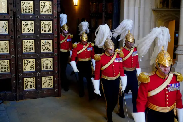 Members of the King's Body Guards of the Honourable Corps of Gentlemen at Arms arrive at the Sovereign's Entrance to the Palace of Westminster