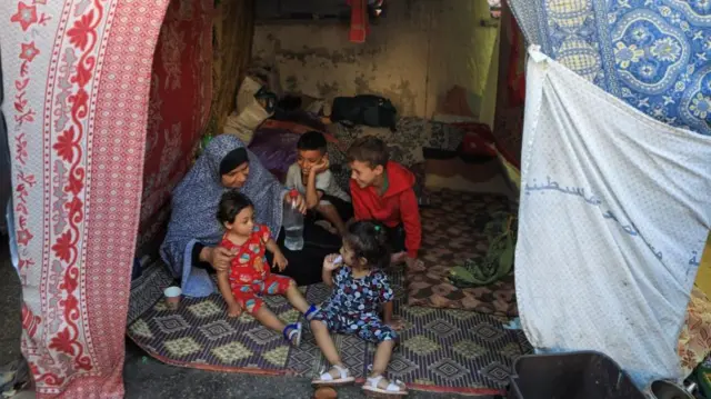 A displaced Palestinian woman, who fled her house due to Israeli strikes, sits with her grandchildren in a makeshift shelter at Shifa hospital, amid the ongoing conflict between Israel and Palestinian Islamist group Hamas, in Gaza City November 5, 2023.