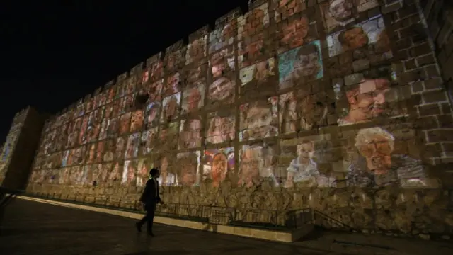 An Ultra-Orthodox Jewish person passes the wall of the old city of Jerusalem during a photo projection of 1,400 victims, in a special ceremony at the Western Wall to mark the 30th day of the Hamas attack on 07 October, at the Western wall in Jerusalem's old city, 06 November 2023.