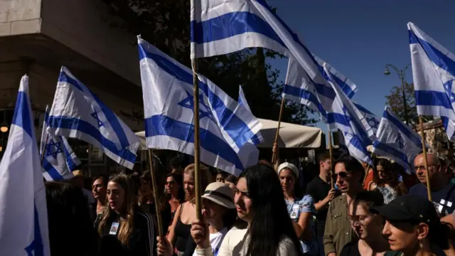 People hold Israeli flags on the day of a ceremony in memory of the victims, on the one-month anniversary of the attack by the Palestinian Islamist group Hamas on October 7th, in Jerusalem November 7, 2023