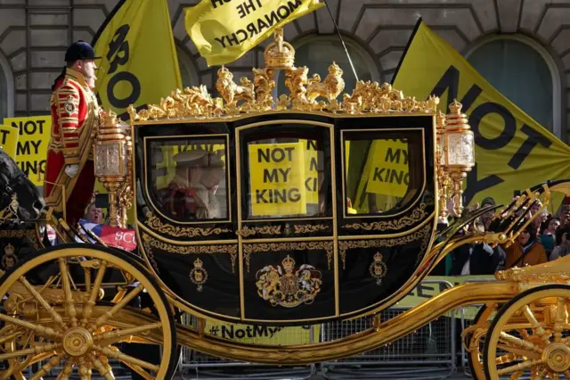 Protesters from the Republic Campaign group holding "Not My King" banners as King Charles passes by in a coach