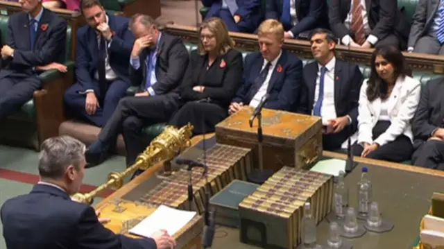 Keir Starmer giving his speech, with the Tory front bench looking on. One minister has his head in his hands.