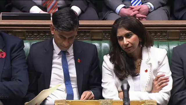 Suella Braverman and Rishi Sunak sitting in Commons, listening to Keir Starmer's reply to the King's Speech. Braverman has her arms folded and Sunak is looking through papers