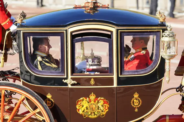 People sit in the carriage with the Imperial State Crown