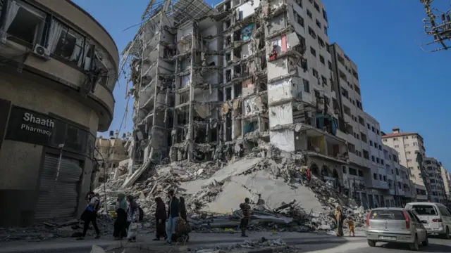 Residents walk past a damaged building as they evacuate Gaza City amid increased military operations in the Gaza Strip, 08 November 2023.