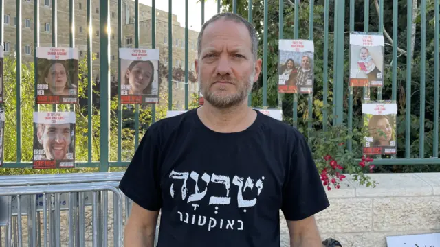 Protester Maoz Inon stands in front of posters showing missing Israelis