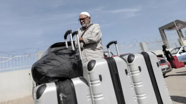 A main waits near the Rafah crossing with his suitcases