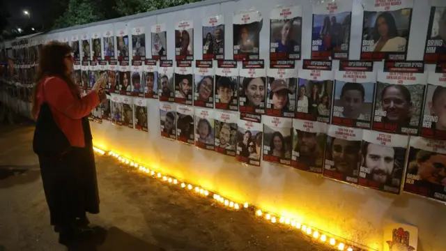 People light candles next to pictures of Israeli hostages and victims as they commemorate one month since the 07 October Hamas attack on Israel during a memorial rally outside the Israeli Knesset in Jerusalem