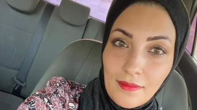 Nour Swirki sitting in a car, wearing a floral dress and a black hijab