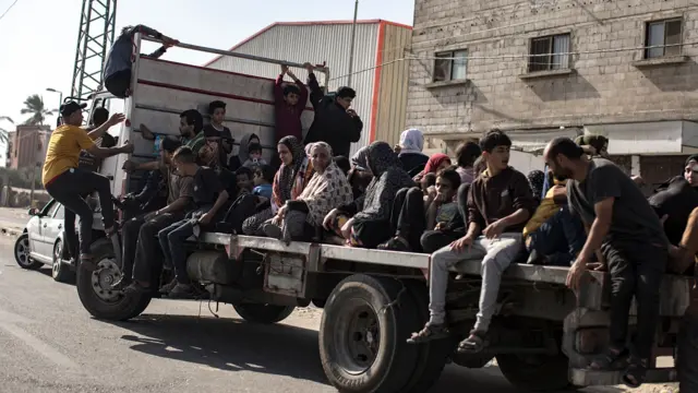 Palestinians, on the back of a pick-up truck, evacuate to the south along Salah al-Din Street