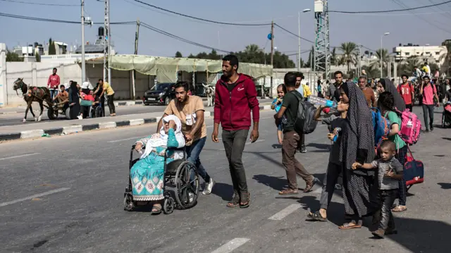 Families, including a woman in a wheelchair, flee to southern Gaza