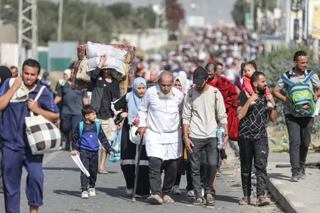 People walking, including a man with a walking stick, another man carrying a small girl