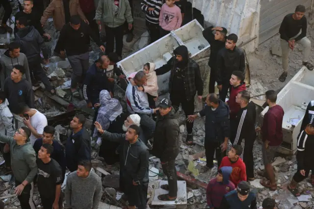 People inspect the destruction following an Israeli strike in the city of Rafah