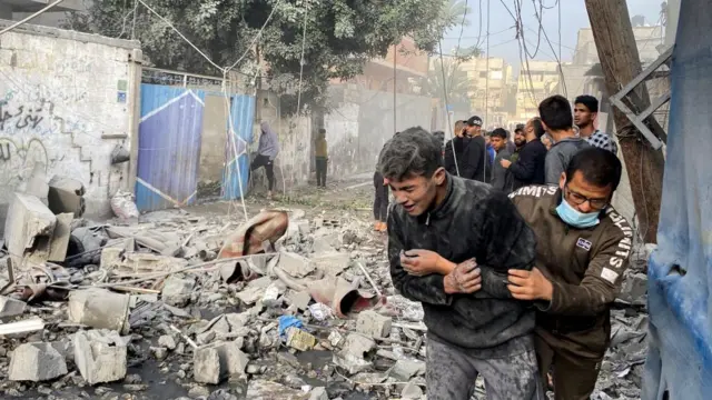 A Palestinian assists a boy following an Israeli strike on a house