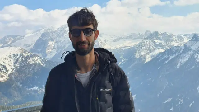 A man poses at the top of a mountain range