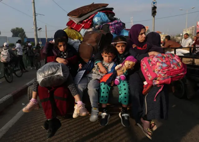 Women and children sit in a trailer, as Palestinians flee their houses in Khan Younis due to Israeli strikes