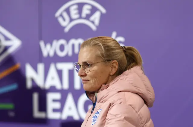 Sarina Wiegman stands in front of a Nations League banner.