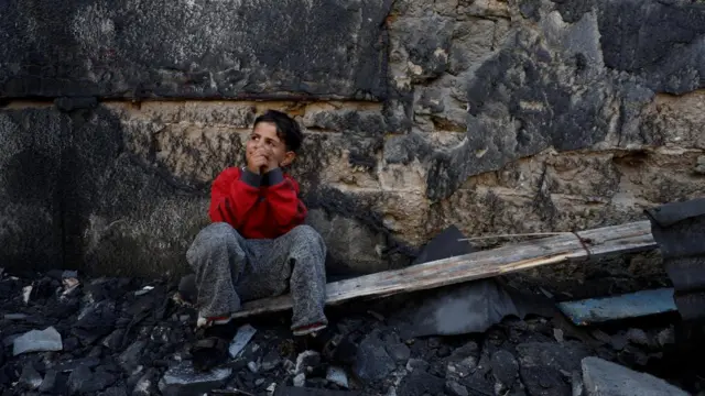 A young boy sits on rubble