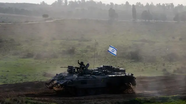 Israeli troops ride on an armoured vehicle