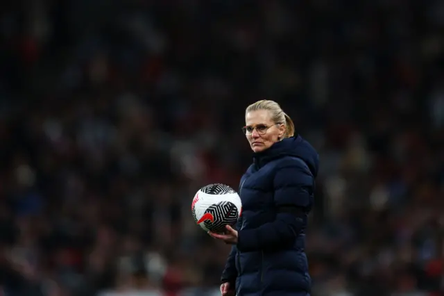 Wiegman holds the ball on the touchline looking pensive.