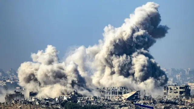 Smoke billows high into the air from a ruined city