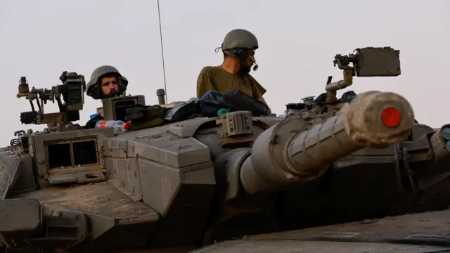 Israeli soldiers look on from a Merkava tank in southern Israel