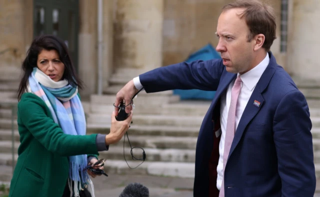 Health Secretary Matt Hancock hands a microphone to his aide Gina Coladangelo (L), as they leave BBC Broadcasting House