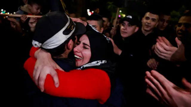 A Palestinian mother cries as she hugs her returned son