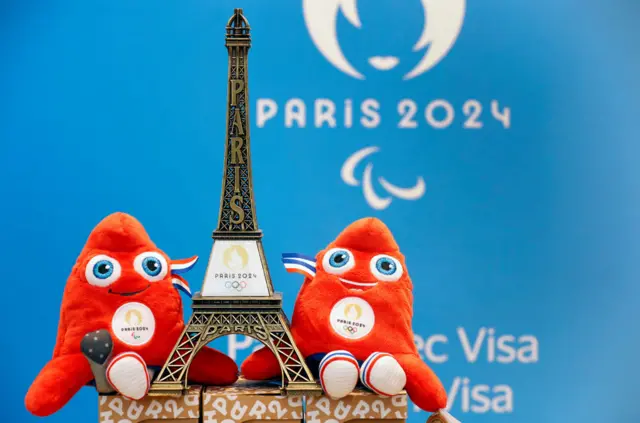 Paris 2024 mascot stuffed toys alongside an eiffel tower replica.