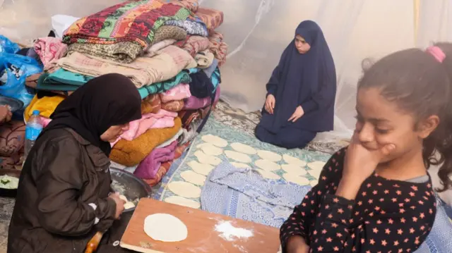 Displaced Palestinians bake bread in a tent