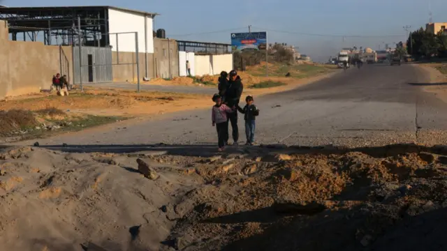 Palestinians navigate around a crater on Salah Al-Din road on the way to Rafah in southern Gaza