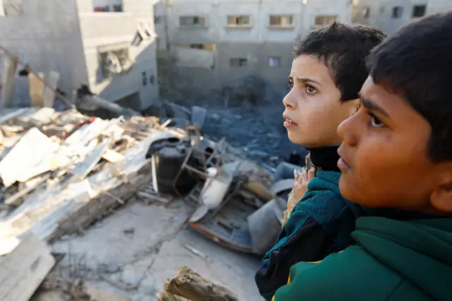 Palestinian children look at damaged buildings