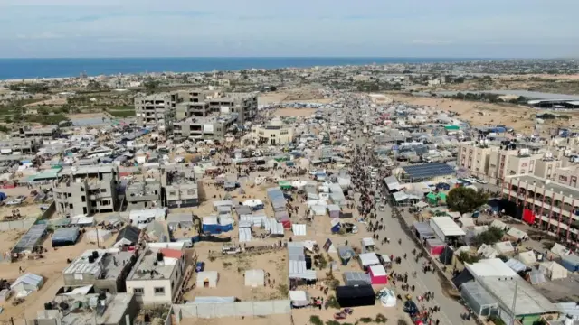 Displaced Palestinians walk among tents in Rafah