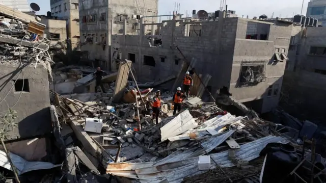 Palestinian rescue workers inspect the damage following Israeli an Israeli strike on a house in Khan Younis