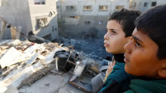 Children look out over damaged buildings in Khan Younis