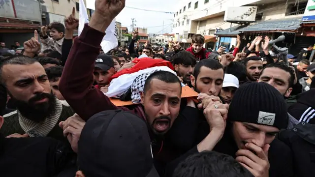 Mourners carry the body of a teenager