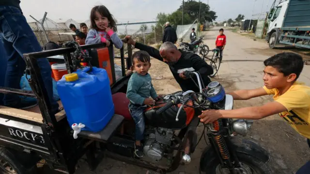 A family pictured with a vehicle which carries large tanks of water