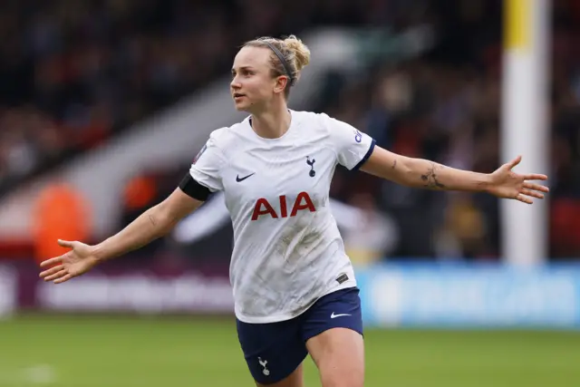 Martha Thomas celebrates scoring a goal by stretching her arms out wide.