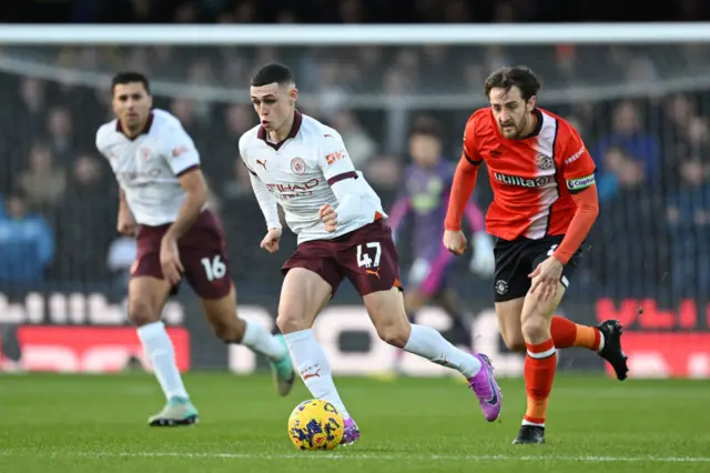 Phil Foden runs with the ball from Tom Lockyer