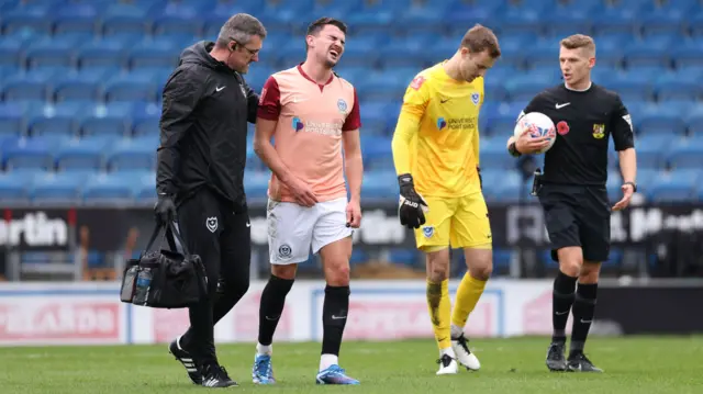 Portsmouth defender Regan Poole walks off the field injured