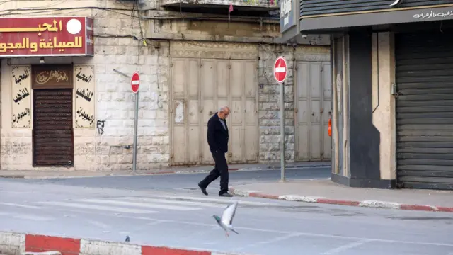 A man walks through an otherwise empty street in Nablus