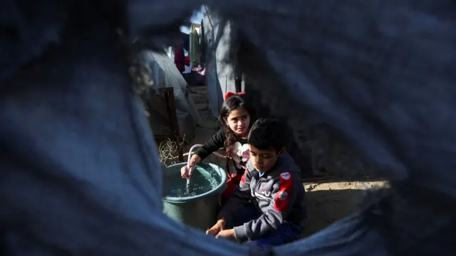 Displaced Palestinian children shelter in a tent camp in Kahn Younis