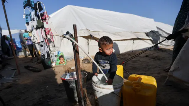 A displaced Palestinian boy, who fled his house due to Israeli strikes, shelters in a tent camp in Kahn Younis