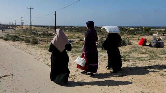 Women seen from behind walking along road in Rafah, southern Gaza,