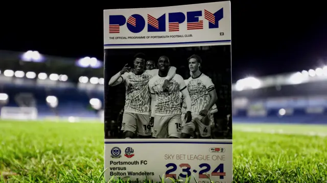 Match programme framing a general shot of the pitch at Fratton Park ahead of Portsmouth v Bolton