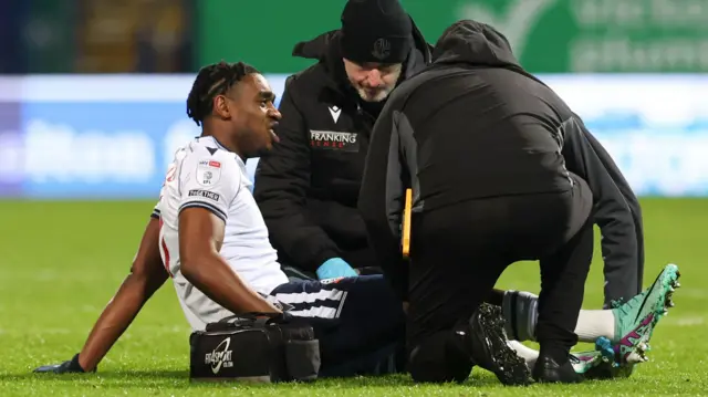 Bolton forward Dan Nlundulu receives treatment on the field for an injury