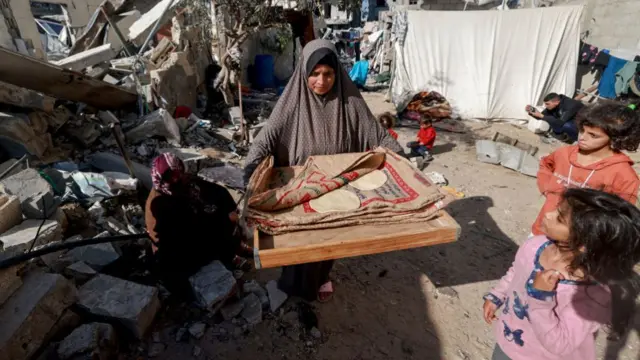 A woman carries bread next to destroyed houses in Rafah on the southern Gaza Strip on 11 December 2023