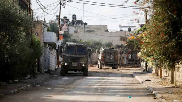 Israeli military vehicles manoeuvre on a road during a raid in Jenin